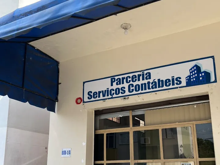 Fachada do escritório da Parceria: toldo azul e placa Parceria Serviços Contábeis sobre a porta de vidro
